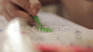 用铅笔特写孩子的手。 孩子用彩色铅笔在纸上画画。